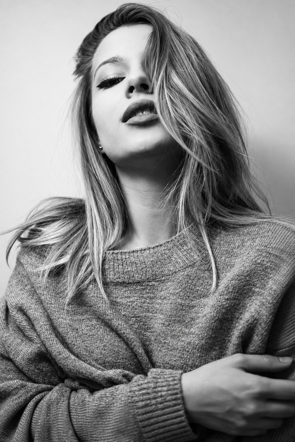 Black-and-white low-angle fashion portrait of a woman in a textured sweater
