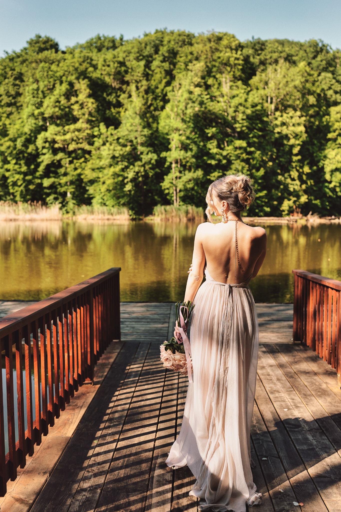Bride overlooking a lake from a wooden terrace