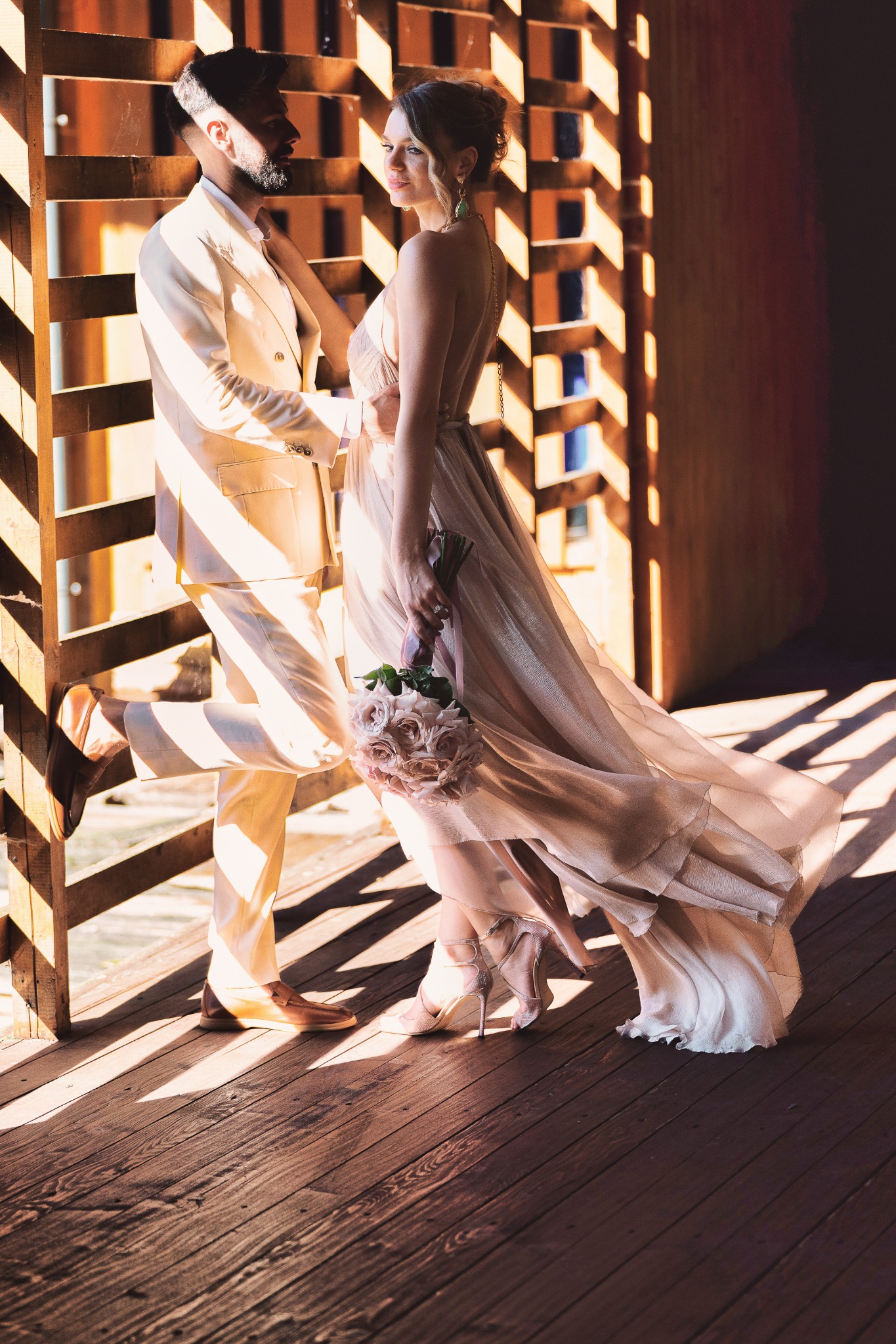 Couple in geometric sunlight inside a wooden passage