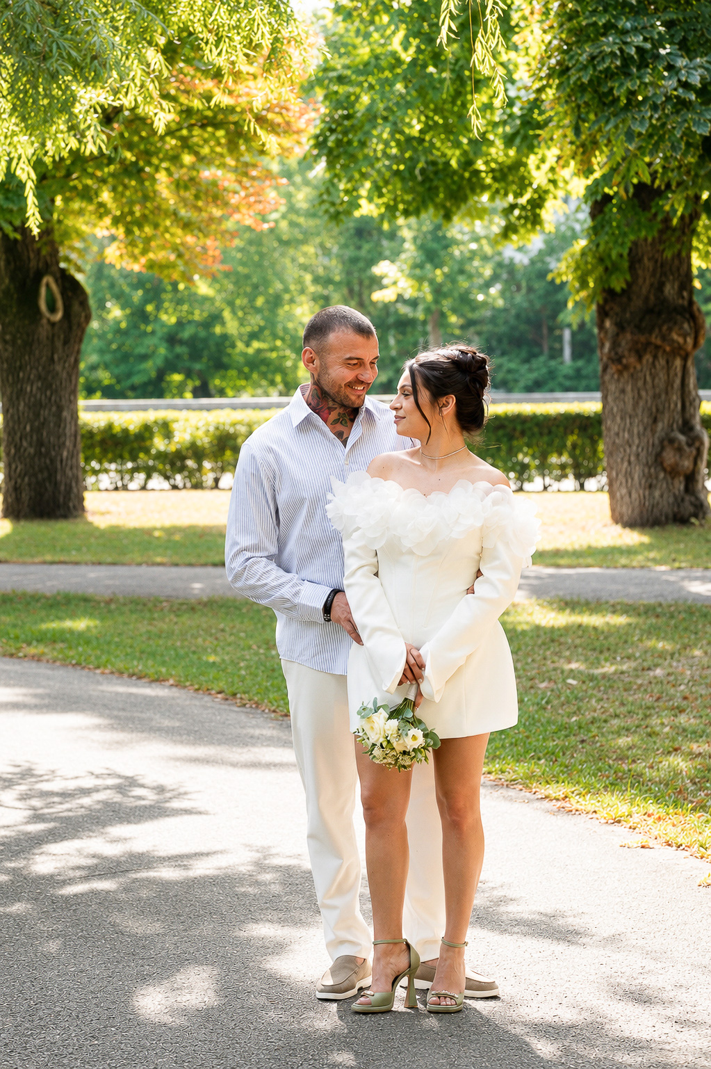 Couple standing on a sunlit tree-lined path