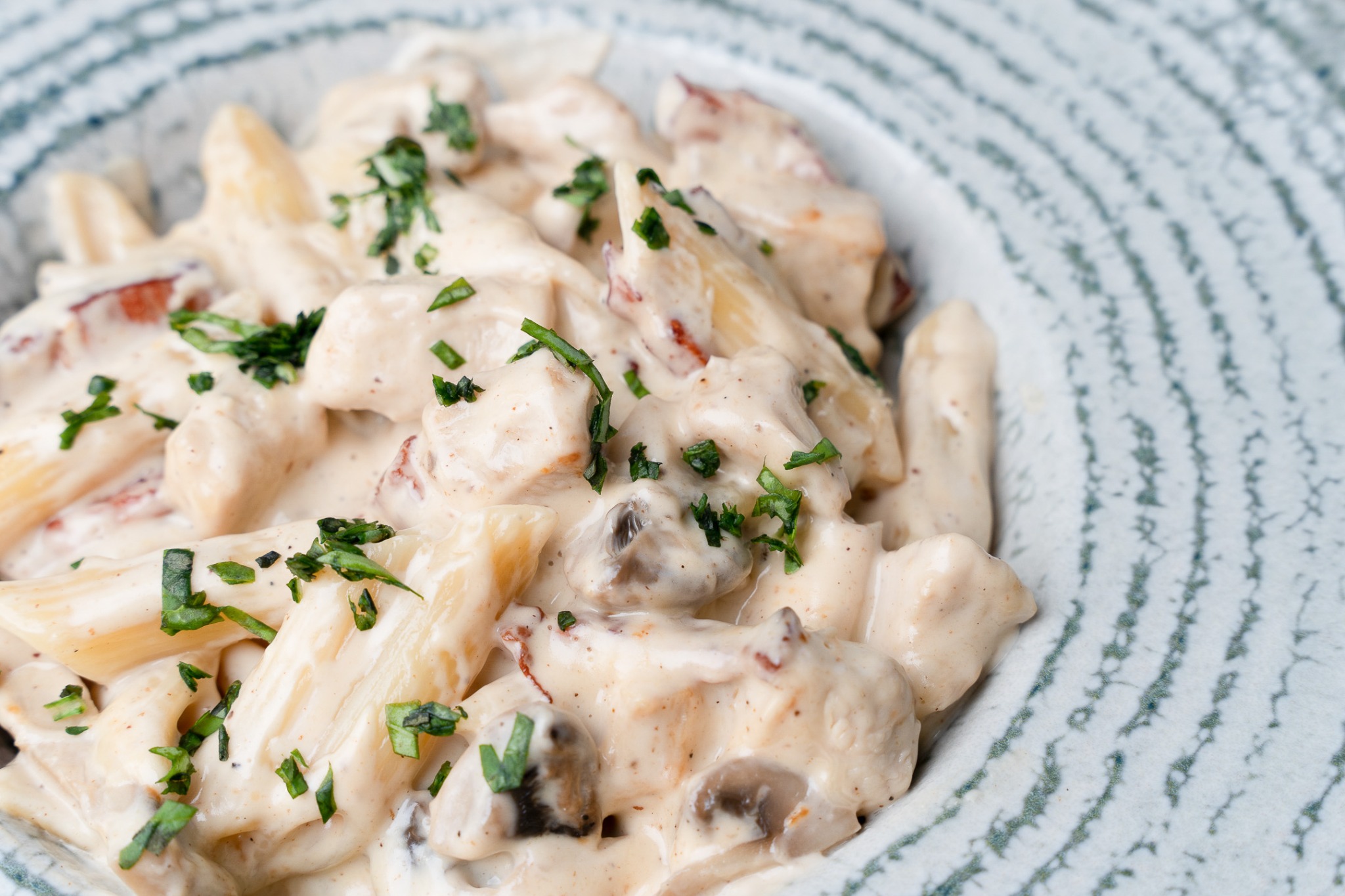 Creamy pasta with herbs on a patterned plate