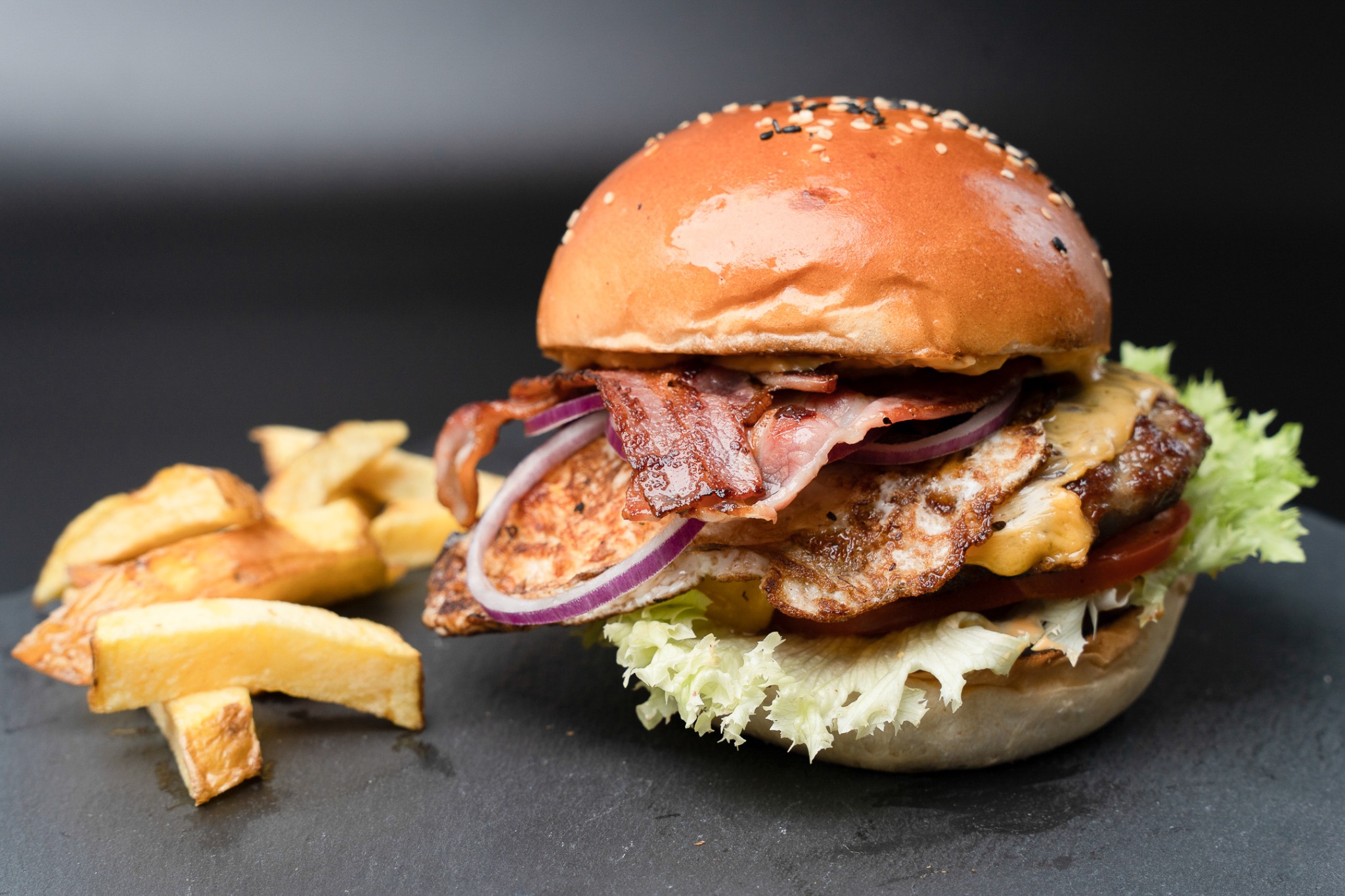 Burger with fries against a dark background