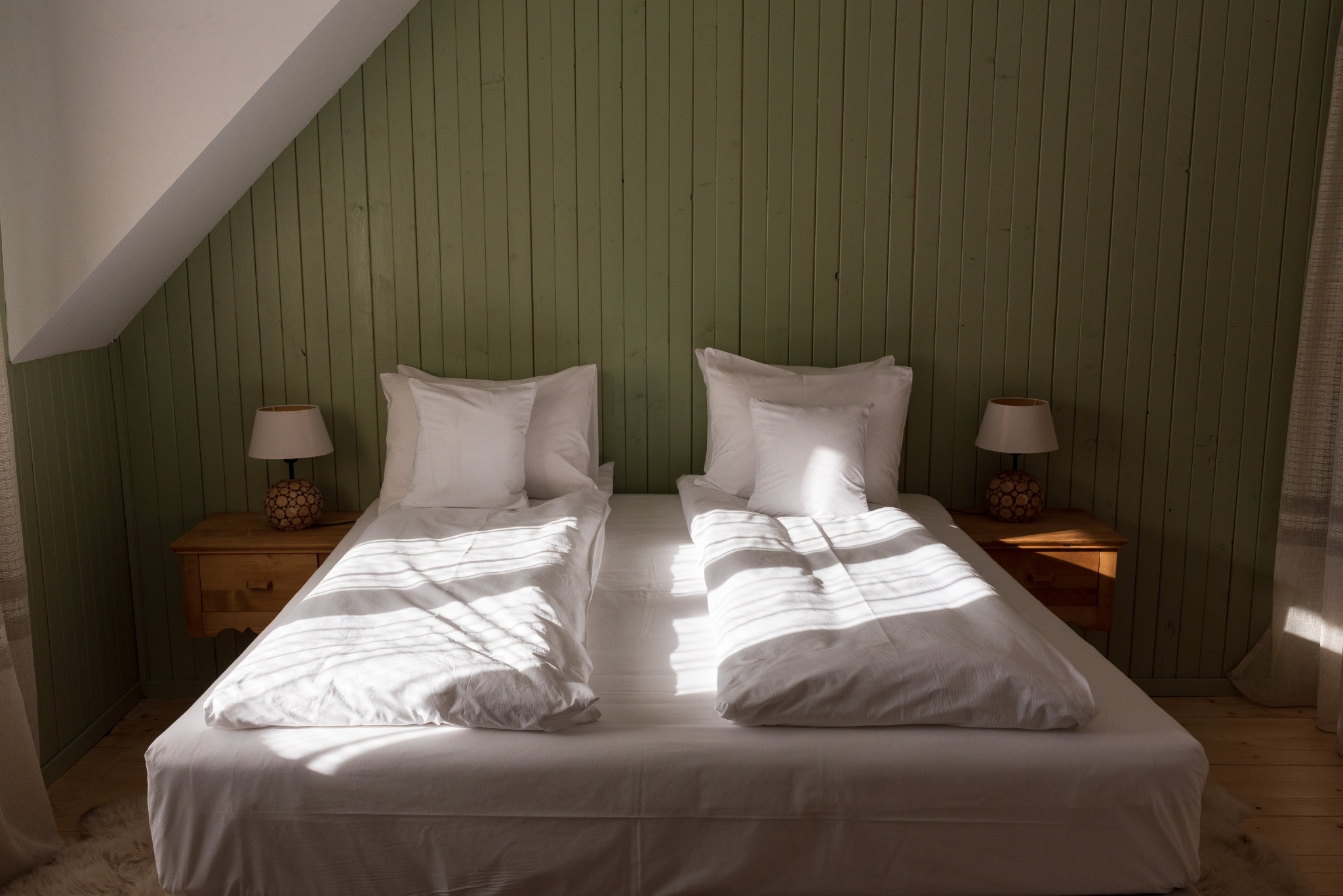 Twin beds against a green paneled wall