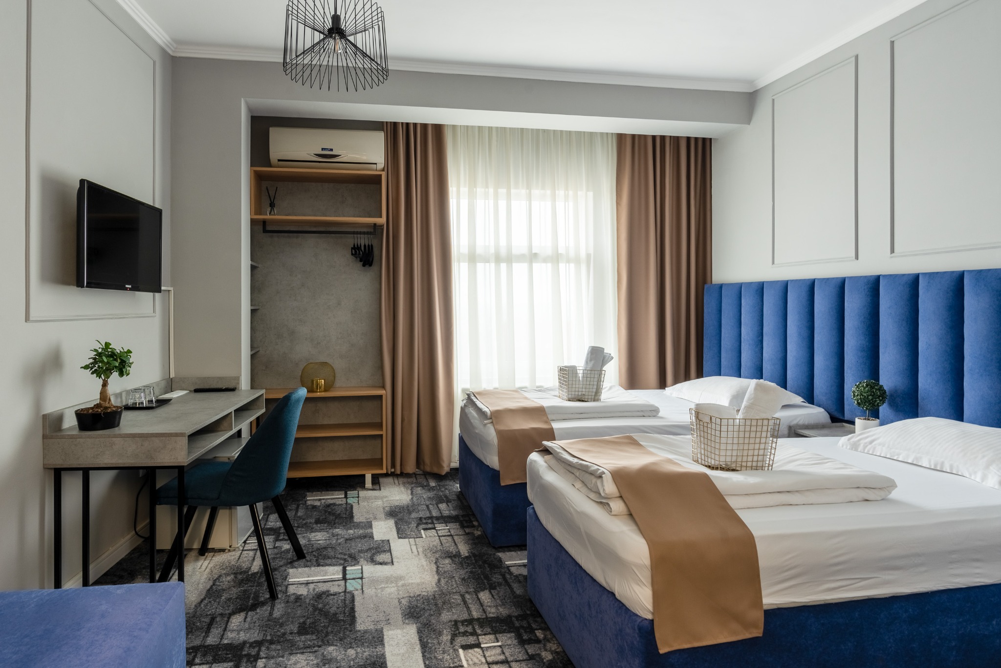 Contemporary guest room with blue headboards